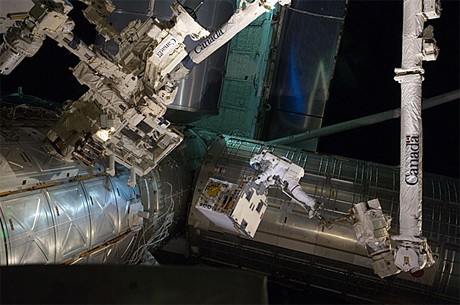 Phi hành gia Ron Garan cưỡi cánh tay máy để đưa máy bơm hỏng vào khoang của tàu con thoi Atlantis. Ảnh: NASA.